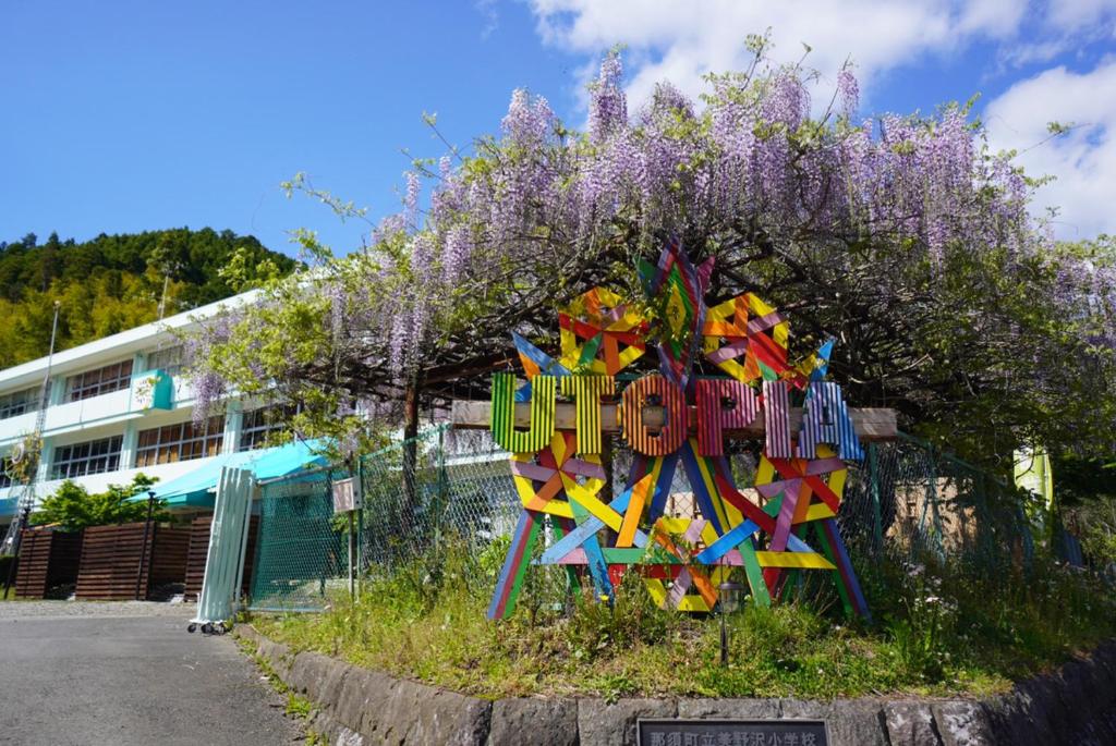 那须町Ｎasu Utopia Minosawa Art Village的紫色花丛前的彩色雕塑