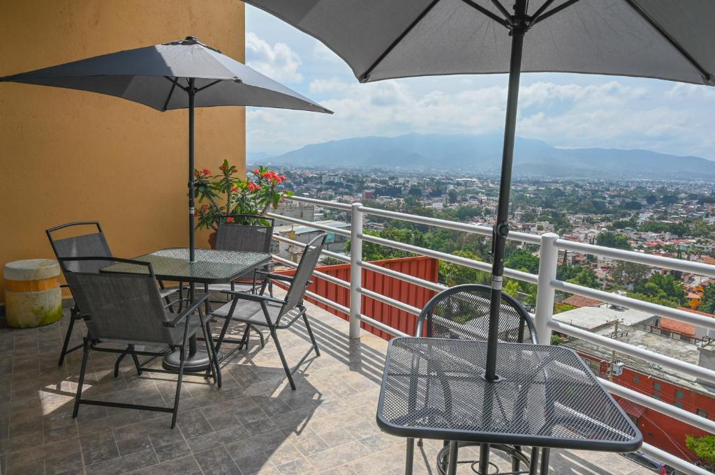 瓦哈卡市Casa LEONOR的阳台配有桌椅和雨伞。