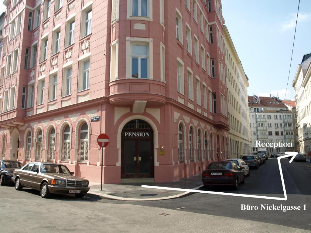 维也纳列支敦士登2号公寓式酒店的一座粉红色的建筑,前面有汽车停放