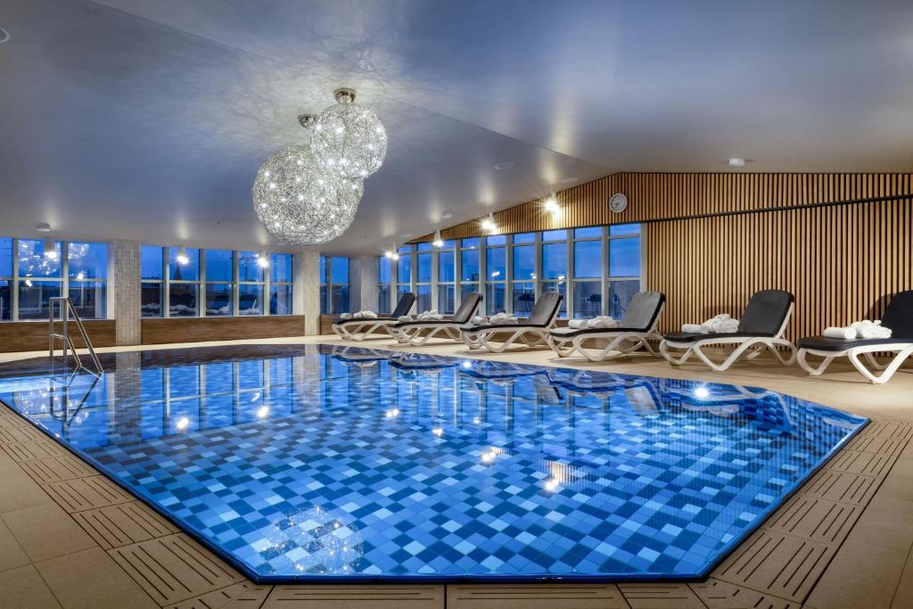 慕尼黑玛丽蒂姆慕尼黑酒店的一个带椅子和吊灯的大型游泳池