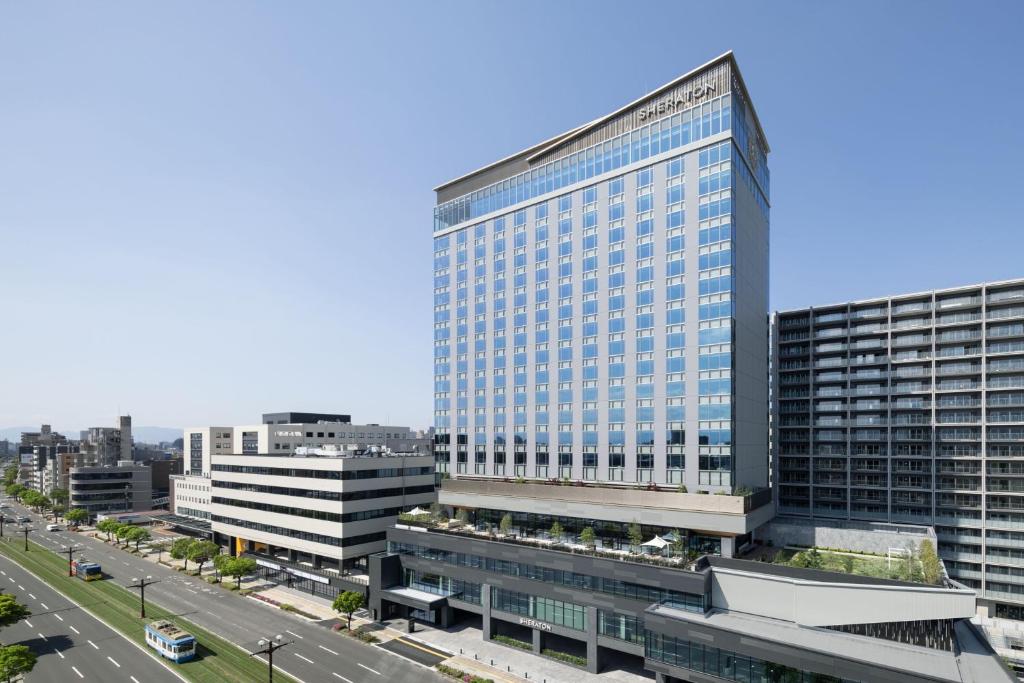 鹿儿岛Sheraton Kagoshima的城市街道上一座高大的建筑,有很多窗户