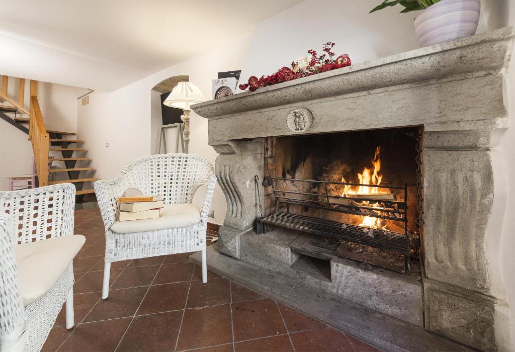 塔尔奎尼亚B&B I Tre Camini的客厅设有壁炉,配有两把白色椅子