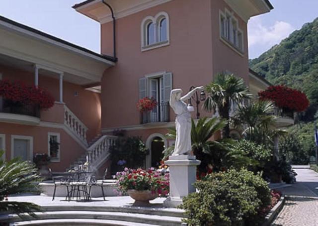 坎诺比奥Hotel Villa Delle Palme的站在房子前面的女人的雕像