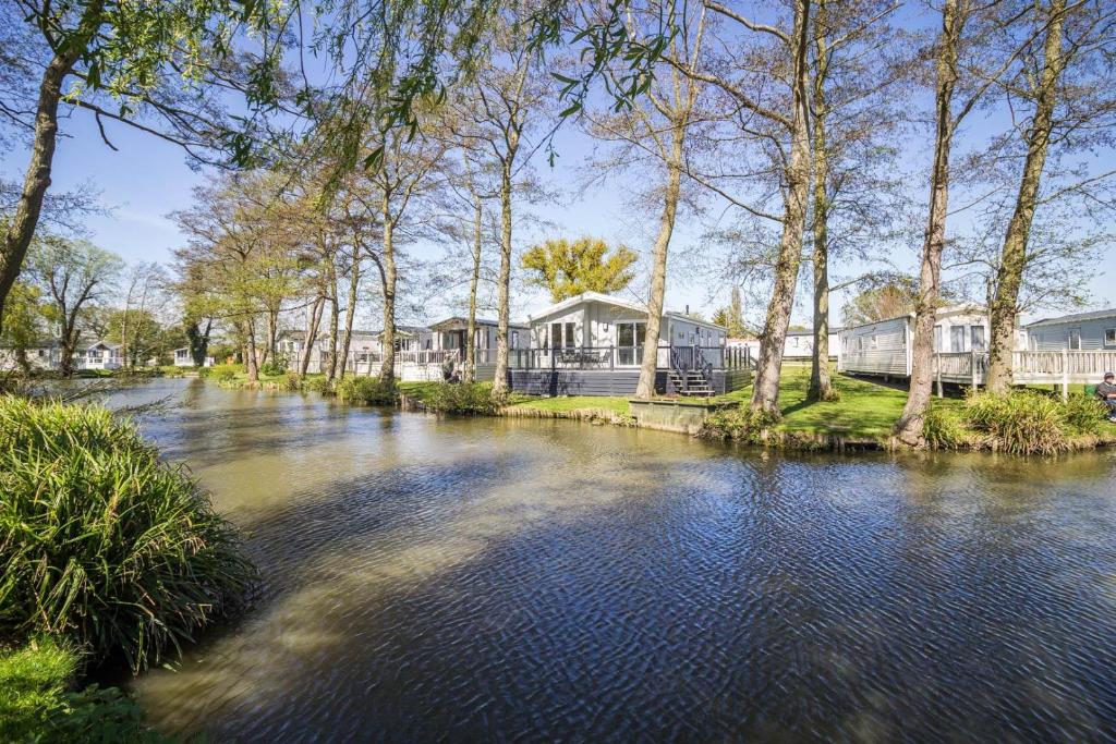 威利Stunning Lodge Boasting Lake Views At Weely Bridge Holiday Park Ref 69005l的一条有房屋和树木的河流