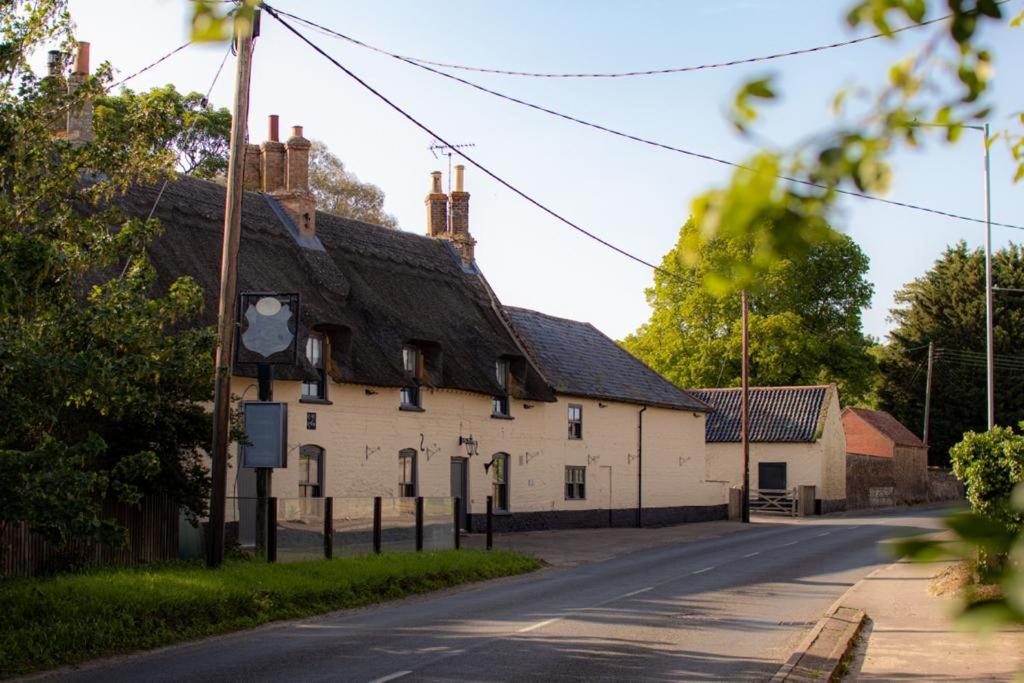 Hockwold cum WiltonBreckland Thatched Cottage的一条白色的街道上,有黑色屋顶