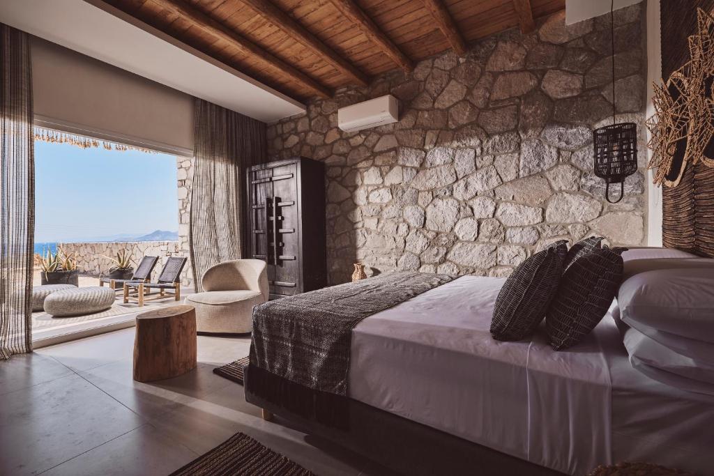 MandrakiaSerenity Suite Milos的一间卧室设有一张床和石墙