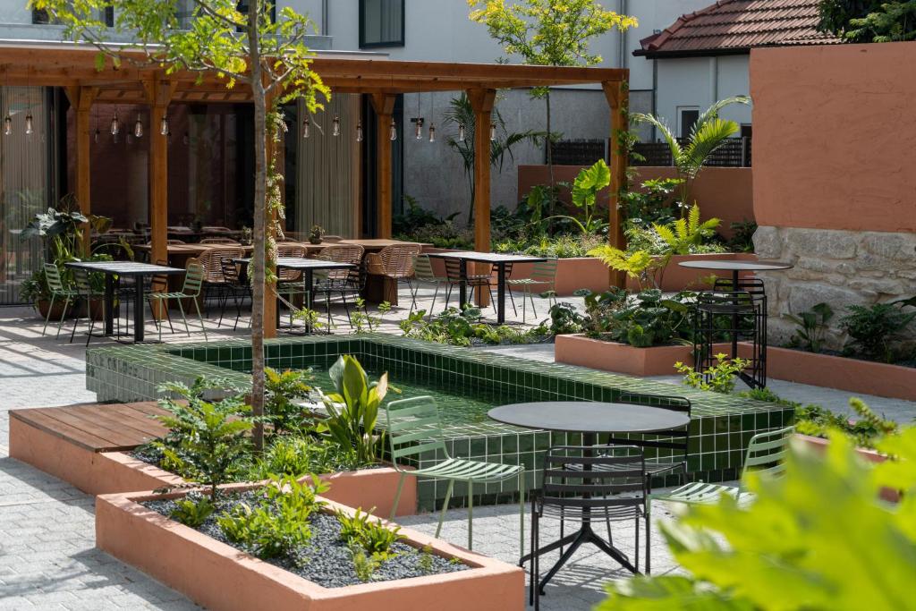 波尔图The Editory Garden Porto Hotel的庭院配有桌椅和树木