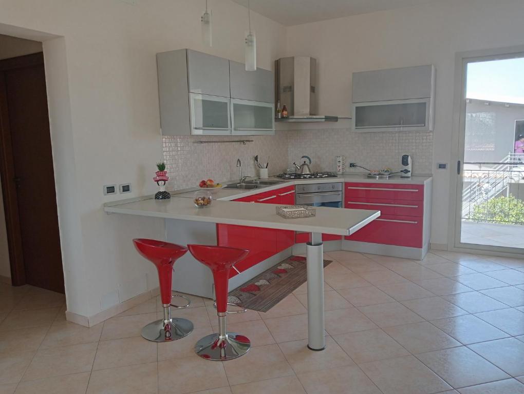 锡拉库扎Villa Gelsemium的一间厨房,配有红色橱柜和红色吧台凳