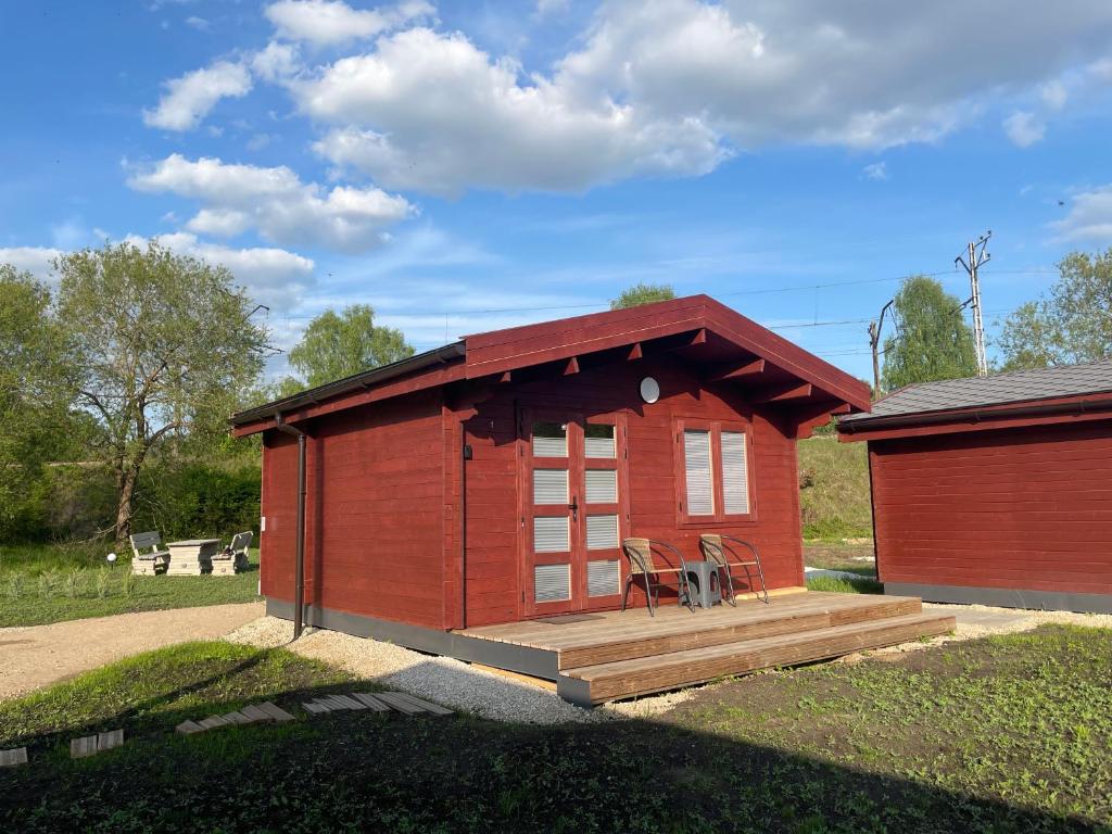 拉脱维亚WOMOCAMP Holzhütte 1的一座红色的小建筑,设有木甲板