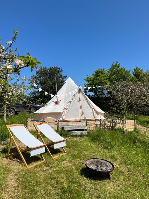 Venn OtteryBowhayes Farm - Camping and Glamping的一个带两把椅子的帐篷和草地上的烧烤架