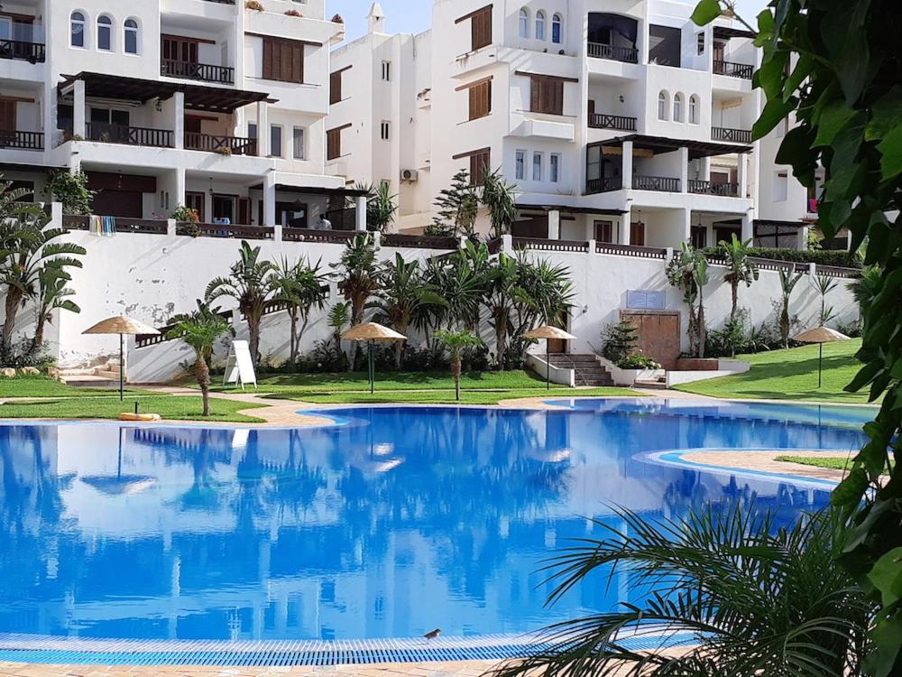 卡博尼格洛Appartement de vacances piscine et plage de Cabo Negro的大楼前的大型蓝色游泳池