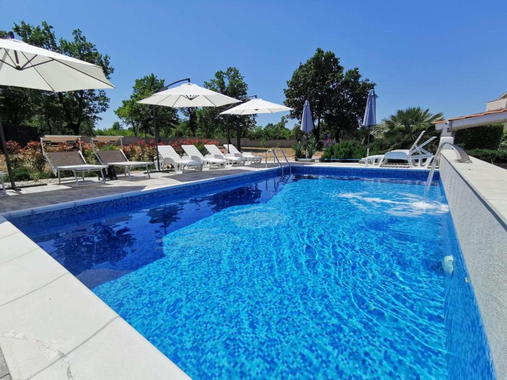 马林斯卡Apartments Lea with pool的一个带椅子和遮阳伞的蓝色游泳池