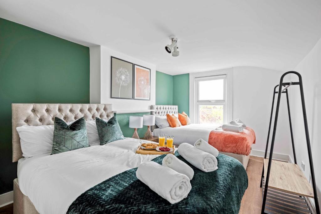 伦敦Parea Living - Hackney, 4-Bedroom Victorian House w Big Garden的一间卧室设有两张带绿色墙壁的床