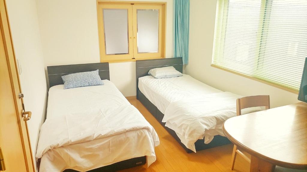 札幌Guest House Kingyo - Vacation STAY 14497的小房间设有两张床和一张桌子