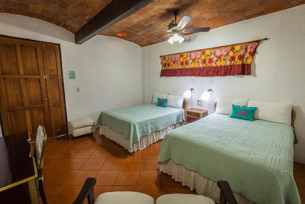 瓦哈卡市Las Mariposas Hotel & Studios的一间卧室配有两张床和吊扇