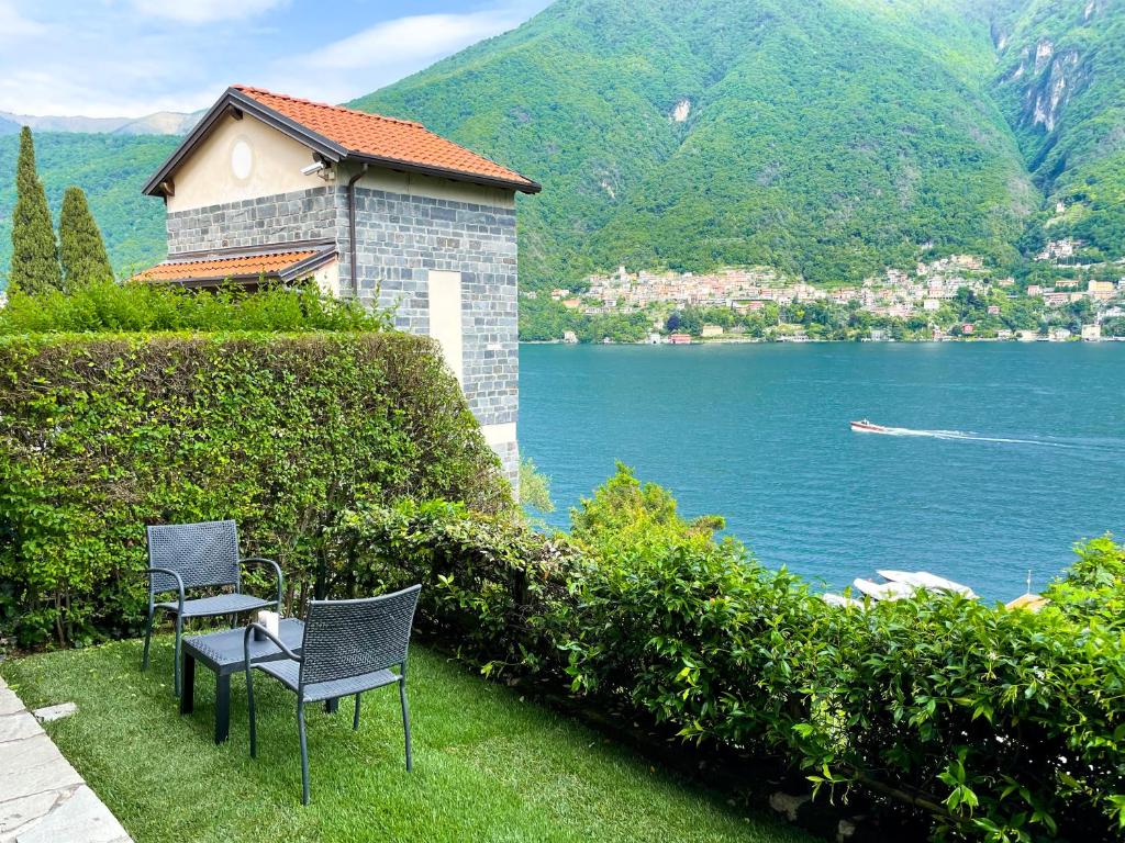 拉利奥Regina di Laglio - Free Parking, Garden, Lake View的两把椅子坐在水边的草上