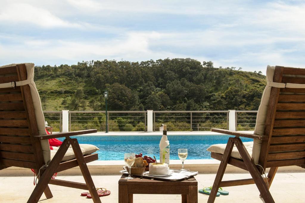 埃里塞拉Beachouse - Surf, Bed & Breakfast的游泳池畔的两把椅子和一张桌子及一瓶葡萄酒
