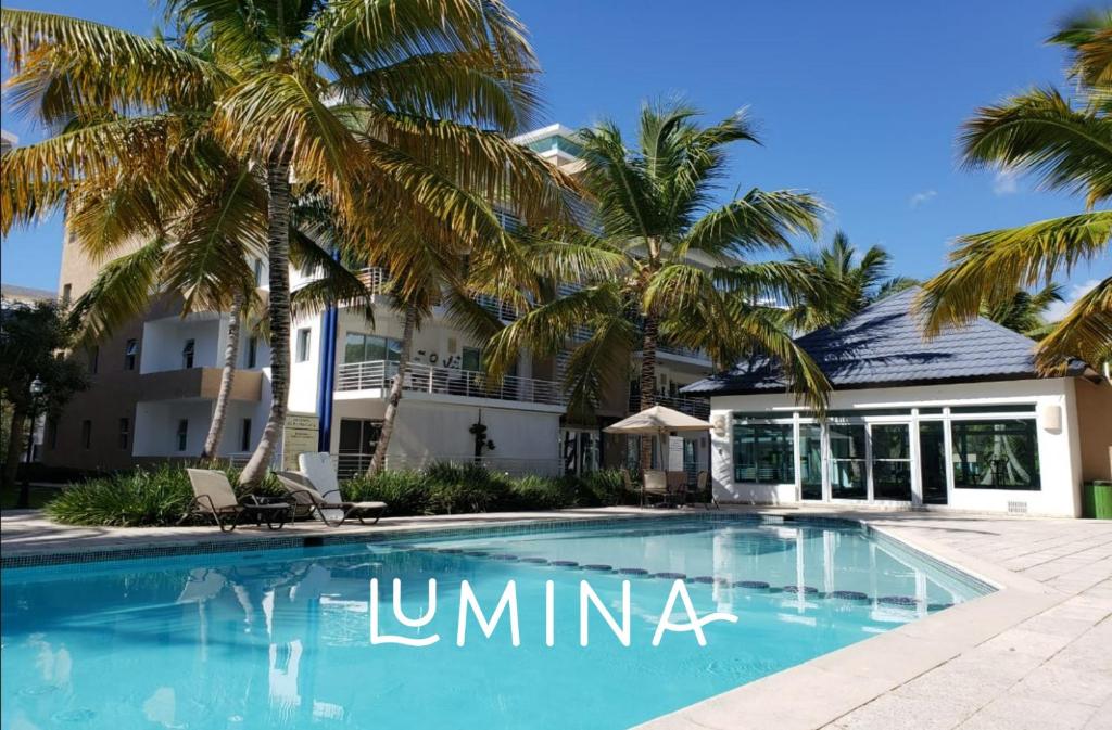 蓬塔卡纳Lumina at Jardines Punta Cana Village的棕榈树屋前的游泳池