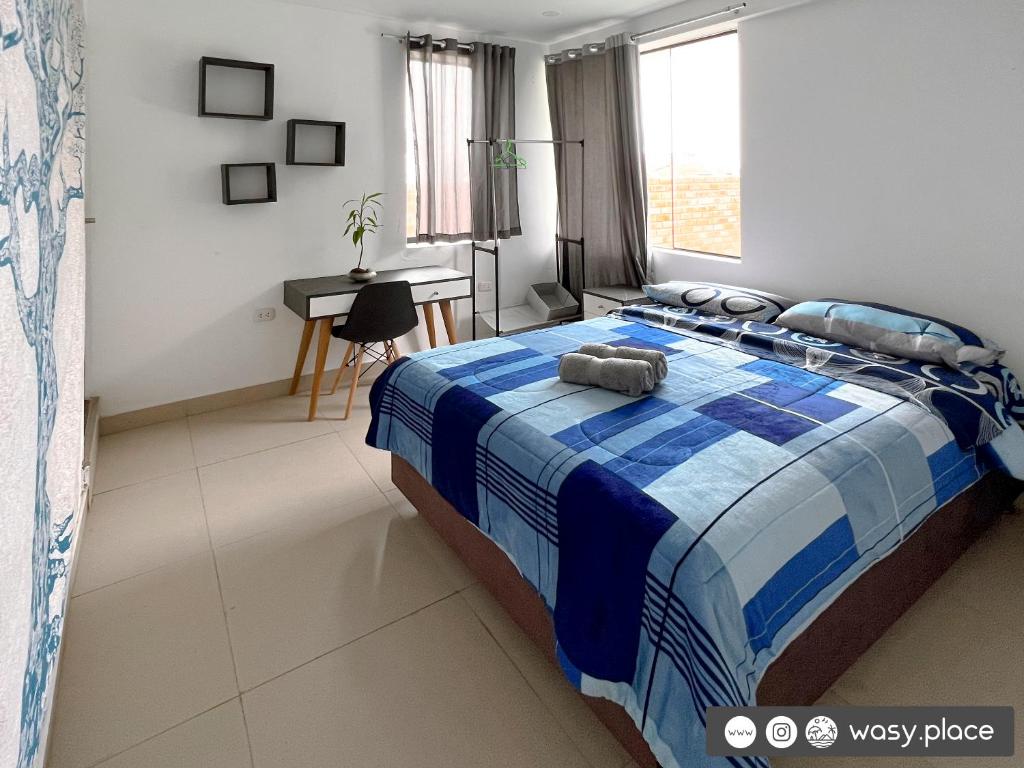万查科Wasy Rentals的卧室配有蓝色和白色的床和书桌。