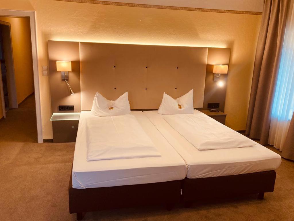 特劳恩施泰因罗森海默霍夫酒店的卧室配有一张带白色床单和枕头的大床。