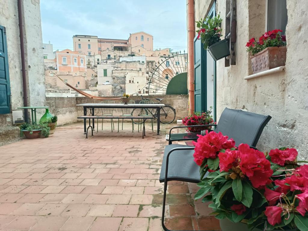 马泰拉Spartivento Apartments的庭院配有桌椅和红色鲜花