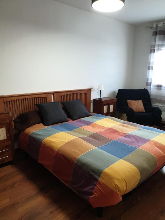 摩拉鲁比罗El Pico del Sombrero, tu lugar para desconectar.的一间卧室配有一张色彩缤纷的床和一把椅子