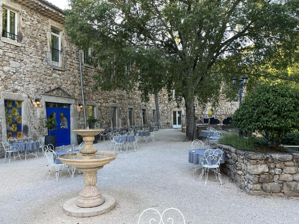 拉让提耶尔Logis Hôtel Restaurant Le Domaine de l'Eau Vive的一座石头建筑,设有喷泉和桌椅