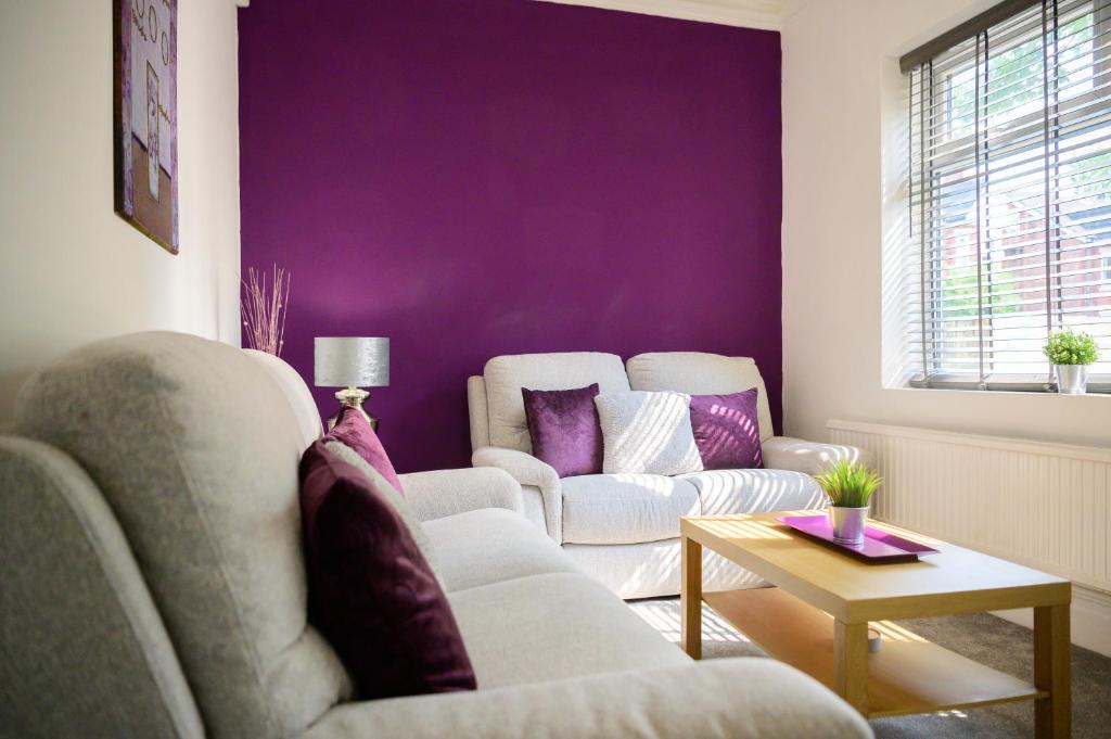 曼彻斯特Purple Blossom, cosy 2 bed apartment, near Didsbury, free parking的客厅配有两张沙发和紫色墙壁