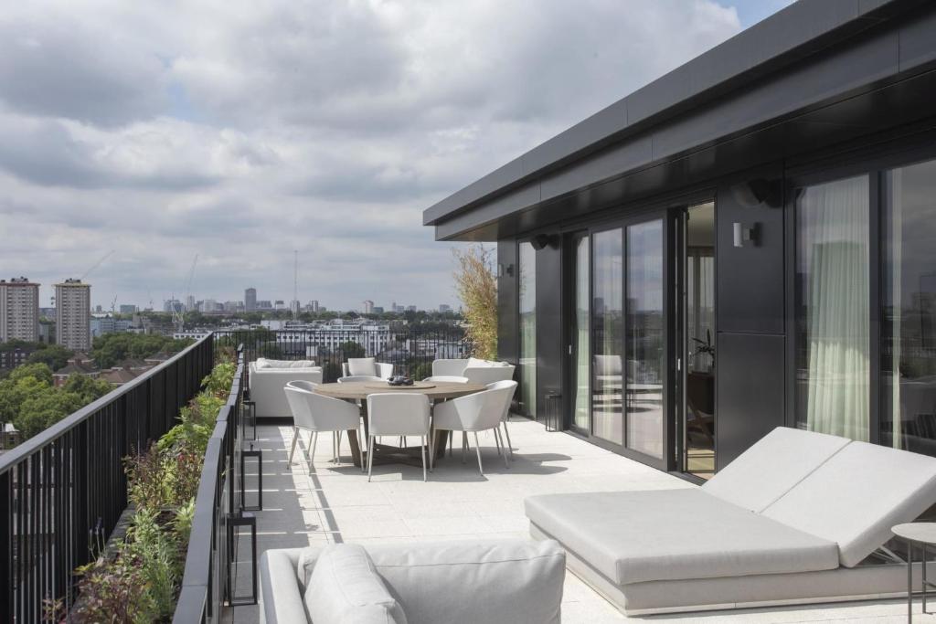 伦敦Modern Apartments at Enclave located in Central London的阳台配有白色家具,享有城市美景。
