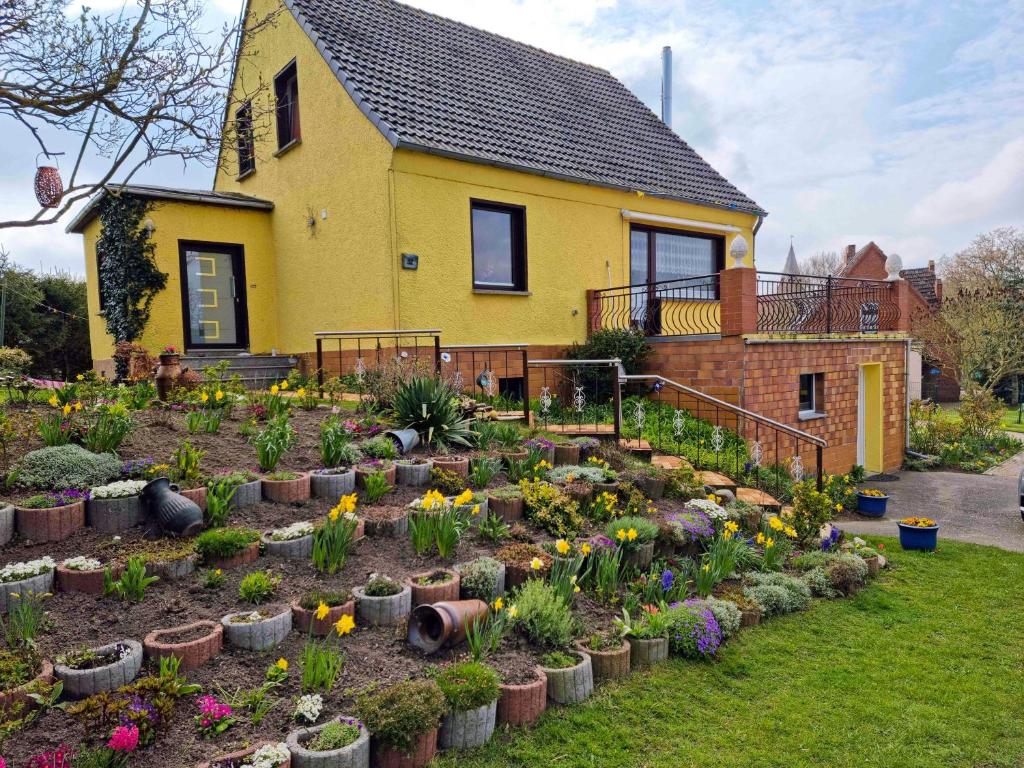 巴特Apartment Kenz-Küstrow的鲜花盛开的黄色房子前面的花园