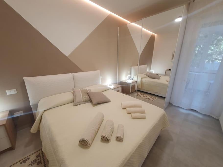 圣温琴佐Lecci al Mare的卧室配有一张带拖鞋的大型白色床。