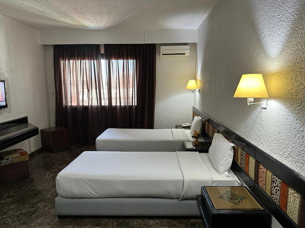 拉巴特Ourida Urban Hotel Rabat的酒店客房设有两张床和电视。