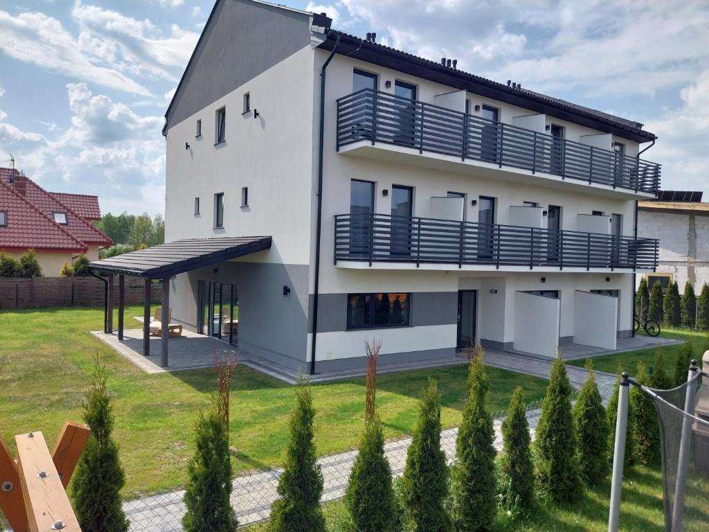 乌斯特卡Villa EDEN USTKA的白色的房子,设有蓝色的阳台和庭院