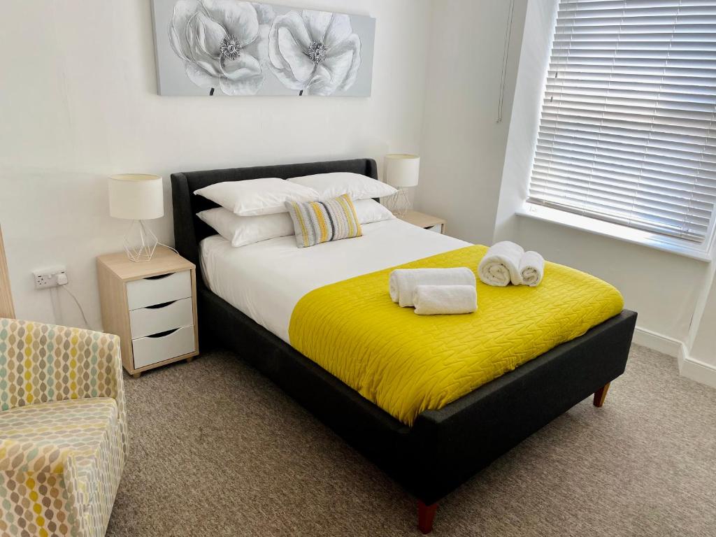 滨海韦斯顿Liberty House的一间卧室配有一张带黄毯的床和一把椅子