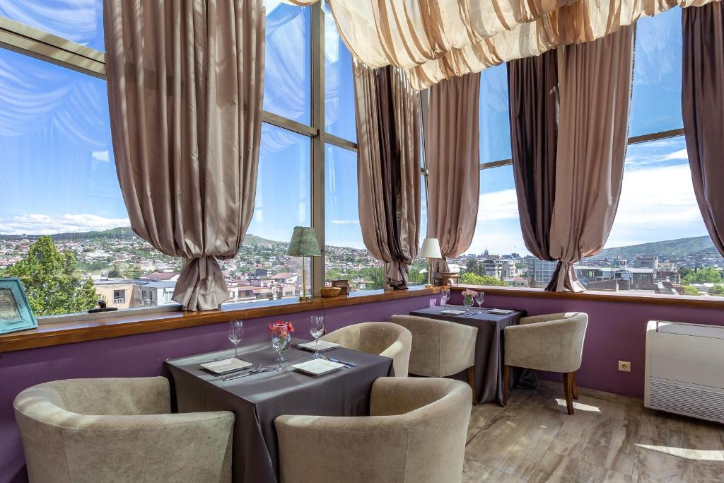 第比利斯A5 Hotel的餐厅设有2张桌子和椅子以及大窗户。