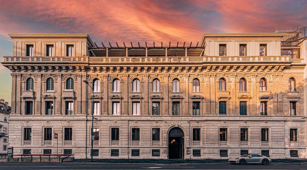 米兰Casa Cipriani Milano的一座大型建筑,前面有停车位