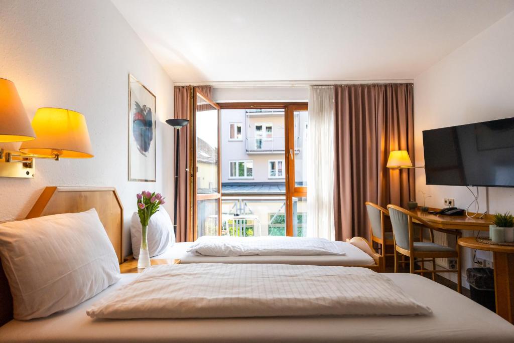 斯图加特CityHotel Feuerbach的酒店客房设有两张床、一张书桌和一个窗户。