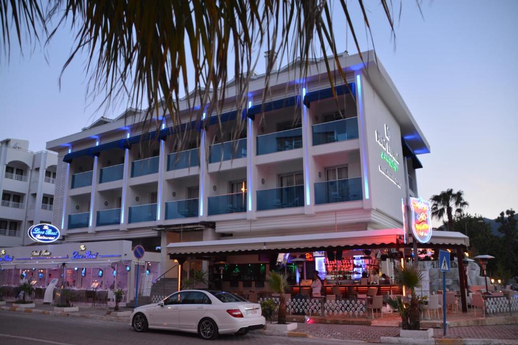 马尔马里斯Devamli Hotel的停在大楼前的白色汽车