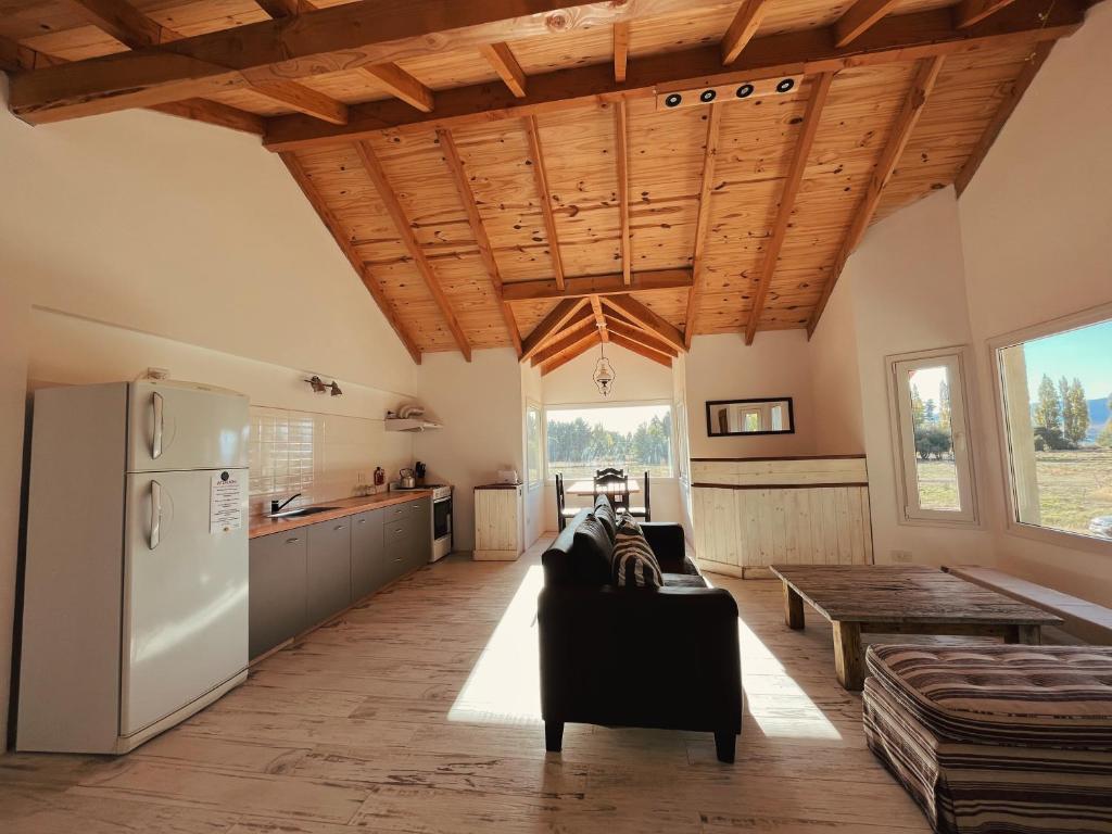 圣卡洛斯-德巴里洛切Casa de Campo La Chacra的一间厨房和一间带木制天花板及冰箱的客厅