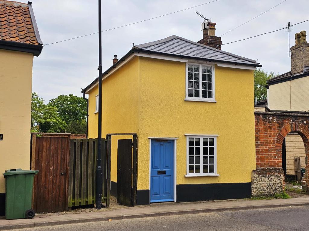 迪斯Perfectly Located Pretty Cottage的街上一扇蓝色门的黄色房子