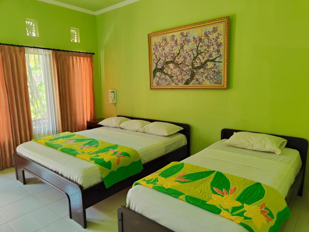 库塔Berlian Inn Kuta Beach的绿墙客房内的两张床