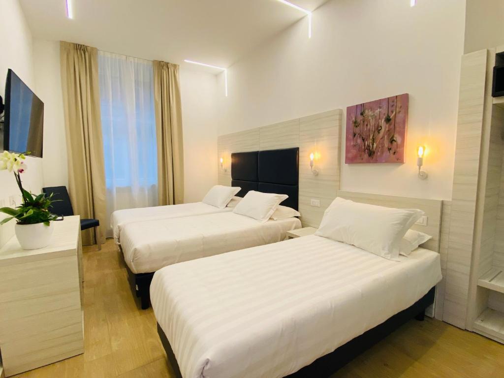 米兰Hotel Fioralba的酒店客房,配有两张带白色床单的床