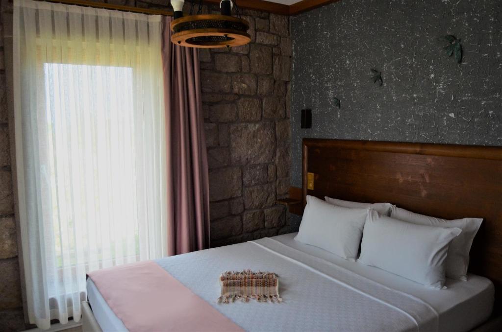 博兹贾阿达岛Le Petit Hotel ve Bağ Evi的一间卧室设有一张大床和窗户