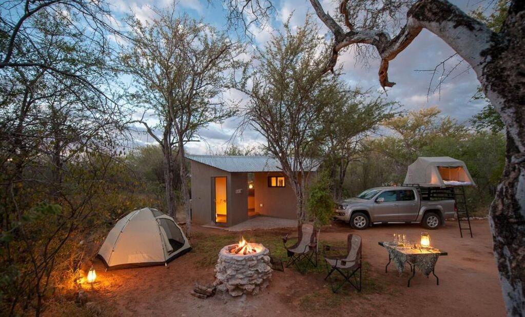 纳穆托尼Onguma Tamboti Campsite的营地,设有帐篷、汽车和餐桌