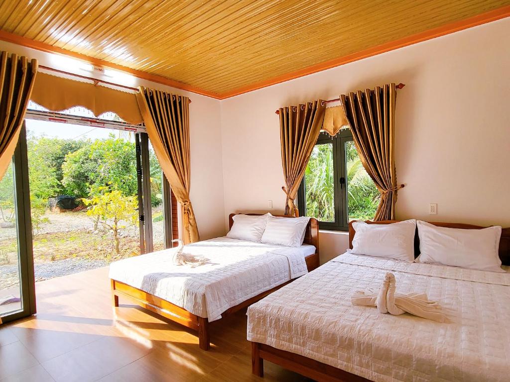 吉仙Thuy Tien Ecolodge的一间卧室设有两张床和大窗户