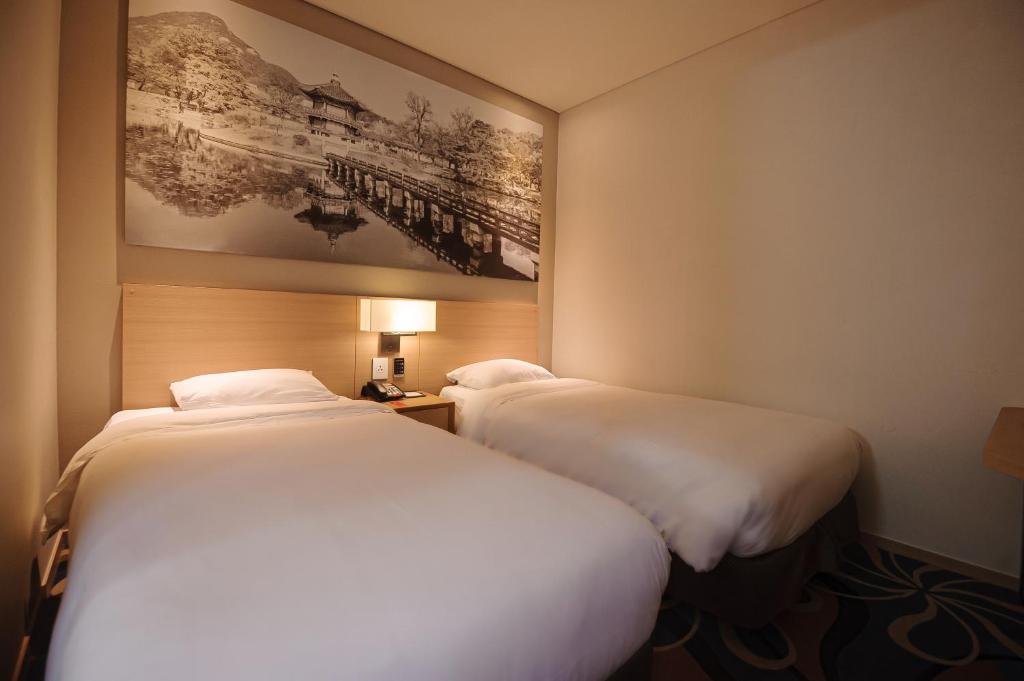 首尔Travelodge Myeongdong Euljiro的两张睡床彼此相邻,位于一个房间里