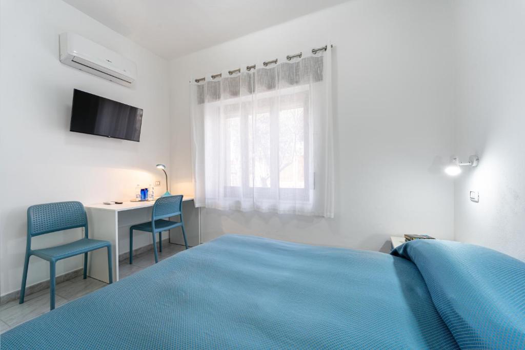 卡尔博尼亚B&B il Rifugio的白色卧室配有蓝色的床和书桌