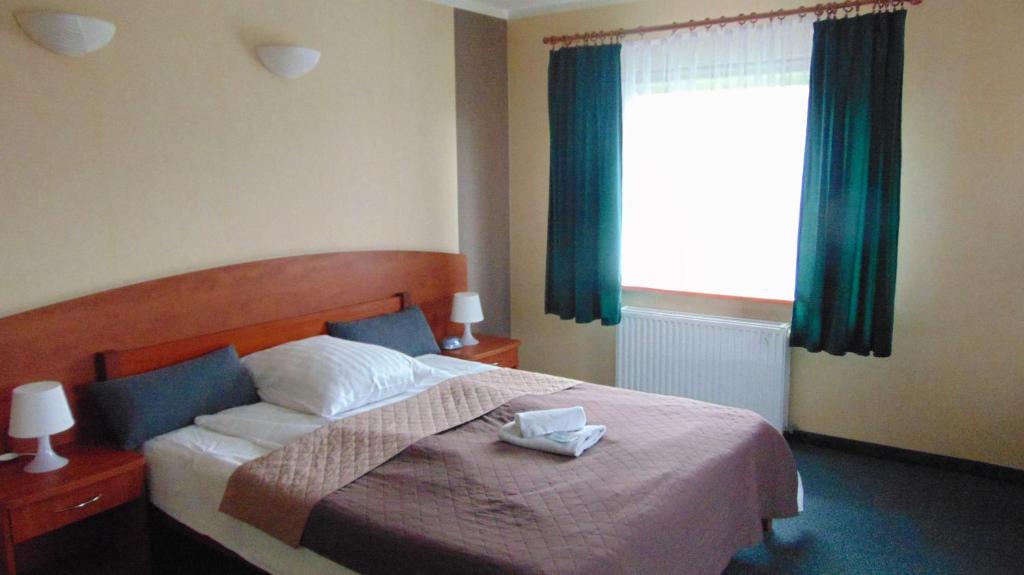 什切青巴慈科酒店的一间卧室设有床铺和一个带绿色窗帘的窗户。