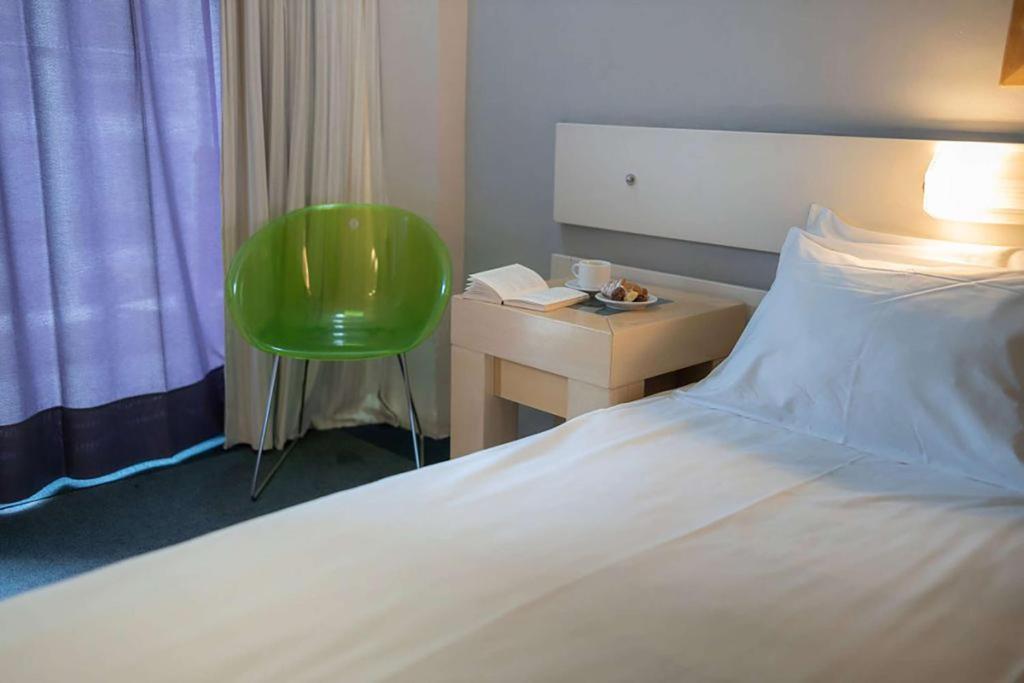 雅典Dorian Inn - Sure Hotel Collection by Best Western的一间卧室配有一张床、一张桌子和一把绿色椅子