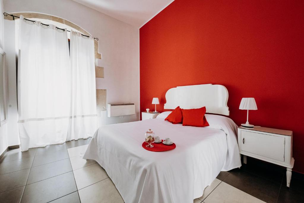 锡拉库扎克雅诺斯住宅酒店的红色的卧室设有一张白色的床铺和红色的墙壁